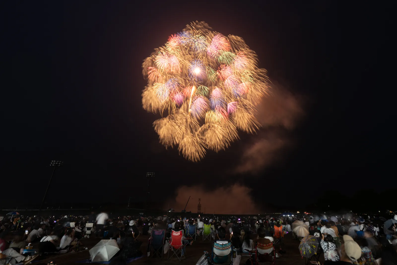浅川の花火で観覧エリアの人々の上に大きく打ち上がる花火